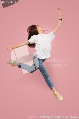 Image of Full length of pretty young woman with mobile phone while jumping