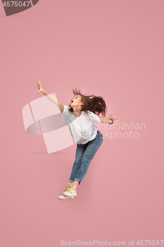 Image of Freedom in moving. Pretty young woman jumping against pink background