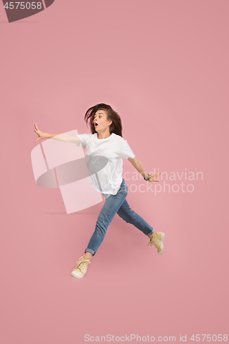 Image of Freedom in moving. Pretty young woman jumping against pink background