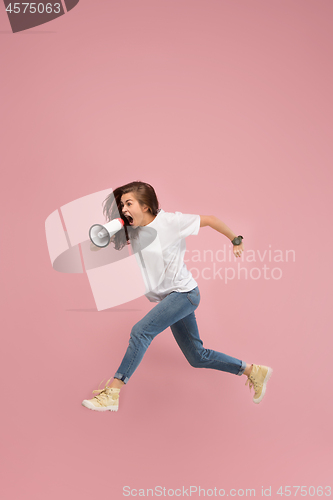 Image of Beautiful young woman jumping with megaphone isolated over pink background