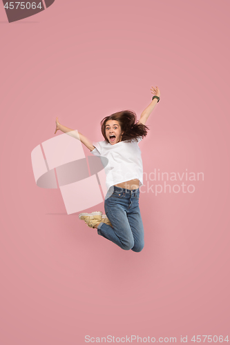 Image of Freedom in moving. Pretty young woman jumping against pink background