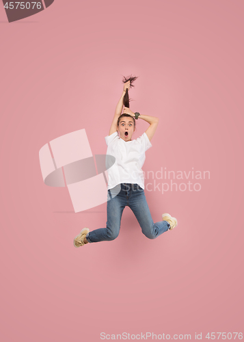 Image of Freedom in moving. Pretty young woman jumping against pink background