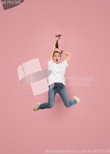 Image of Freedom in moving. Pretty young woman jumping against pink background