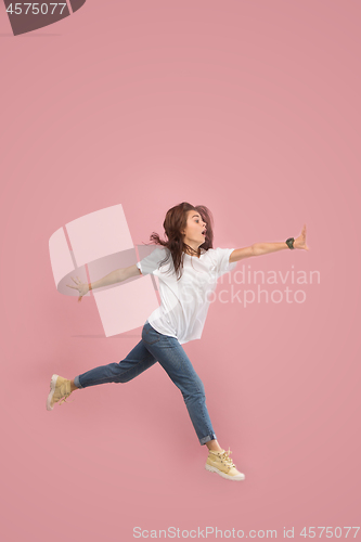 Image of Freedom in moving. Pretty young woman jumping against pink background