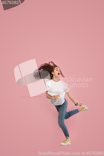 Image of Freedom in moving. Pretty young woman jumping against pink background