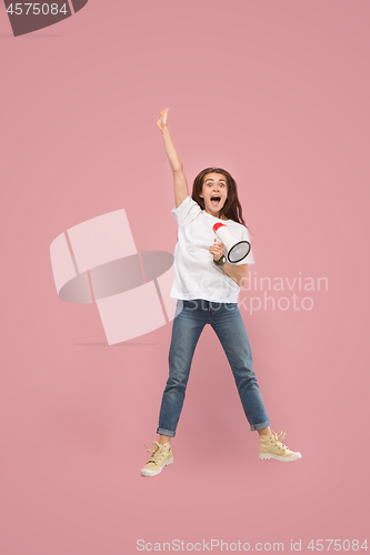 Image of Beautiful young woman jumping with megaphone isolated over pink background