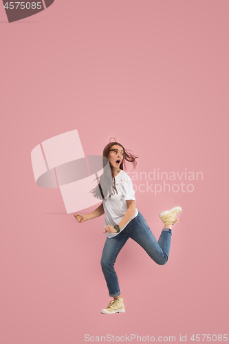 Image of Freedom in moving. Pretty young woman jumping against pink background