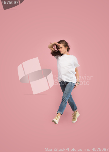 Image of Freedom in moving. Pretty young woman jumping against pink background