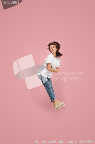 Image of Freedom in moving. Pretty young woman jumping against pink background