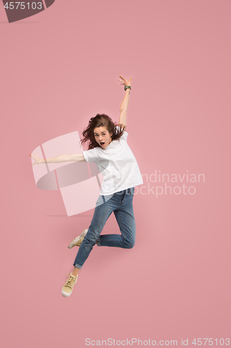 Image of Freedom in moving. Pretty young woman jumping against pink background