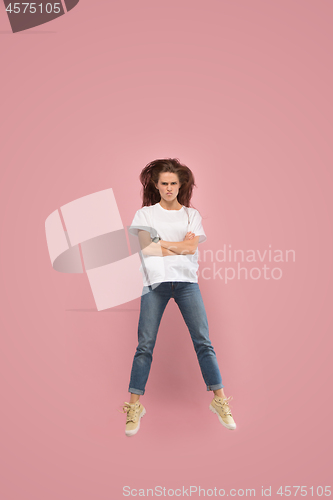 Image of Freedom in moving. Pretty young woman jumping against pink background