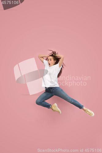 Image of Freedom in moving. Pretty young woman jumping against pink background