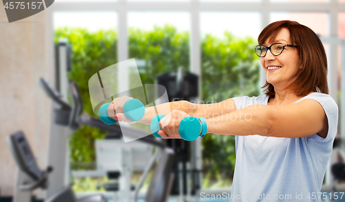 Image of happy old woman with dumbbells exercising in gym