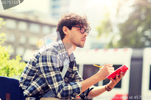 Image of man with notebook or diary writing on city street