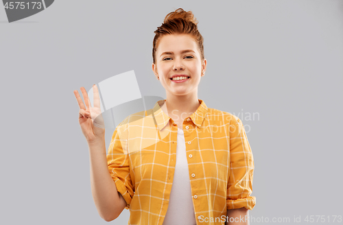 Image of red haired teenage girl showing three fingers