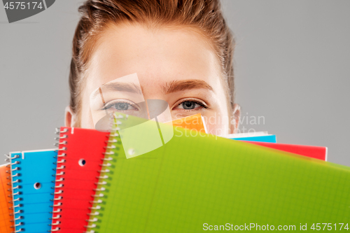 Image of close up of teenage student girl behind notebooks