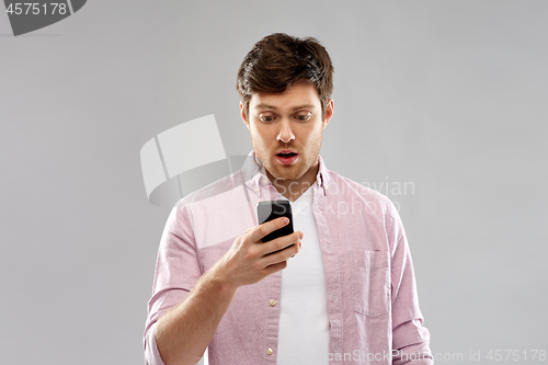 Image of embarrassed young man looking at smartphone