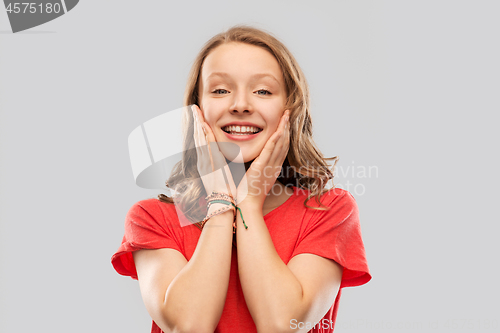 Image of smiling teenage girl in red t-shirt over grey