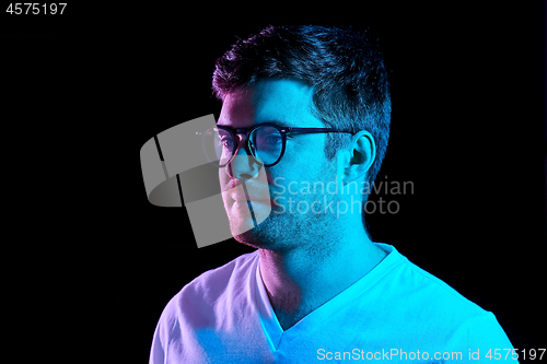 Image of man in glasses over neon lights in dark room