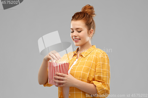 Image of smiling red haired teenage girl eating popcorn