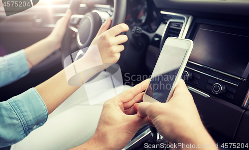 Image of happy man and woman with smartphone driving in car