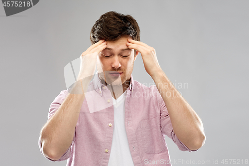 Image of unhappy young man suffering from headache