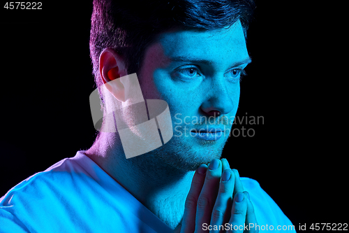 Image of man praying god over ultra violet neon lights