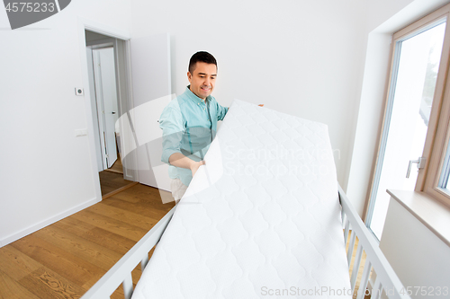 Image of father arranging baby bed with mattress at home