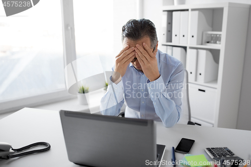 Image of stressed businessman with laptop working at office