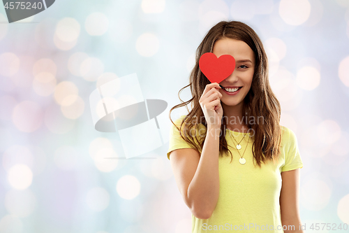 Image of smiling teenage girl covering her eye by red heart