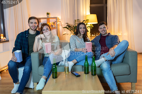 Image of friends with beer and popcorn watching tv at home