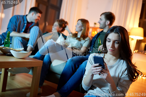 Image of young woman with smartphone at home party