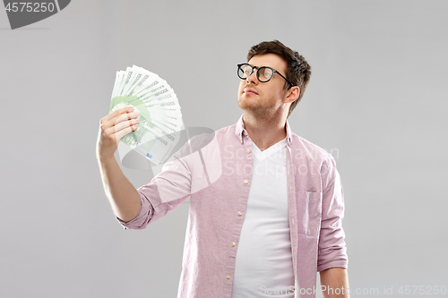 Image of proud young man in glasses with fan of euro money