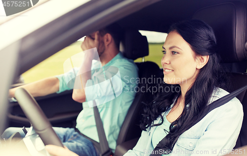 Image of woman driving car and man covering face with palm