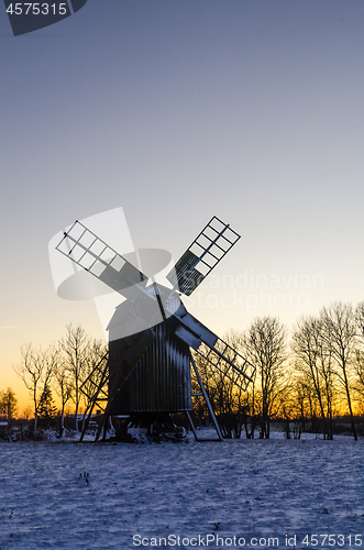 Image of Wooden windmill by sunset in winter time