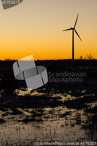 Image of Windmill silhouette in a plain landscape with water reflections