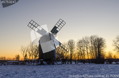 Image of Traditional wooden windmill by sunset in winter season