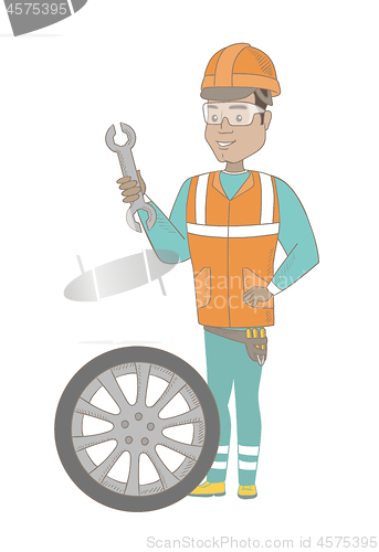 Image of Young hispanic mechanic with tyre and spanner.