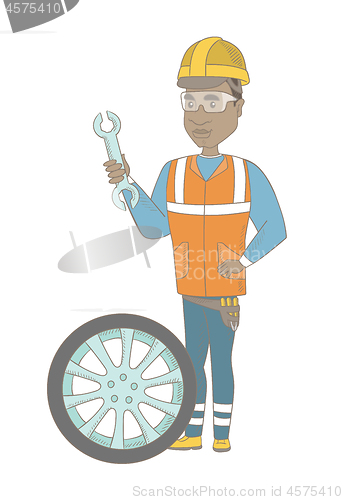 Image of Young african mechanic with tyre and spanner.