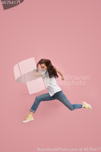 Image of Freedom in moving. Pretty young woman jumping against pink background