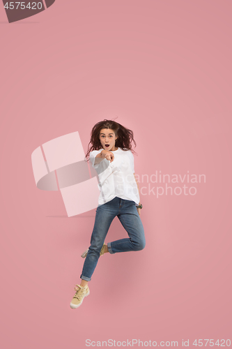 Image of Freedom in moving. Pretty young woman jumping against pink background