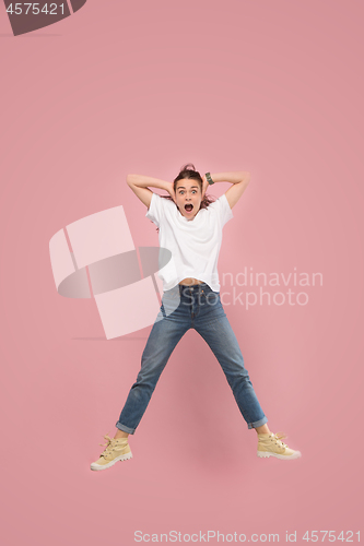 Image of Freedom in moving. Pretty young woman jumping against pink background