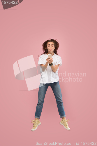 Image of Full length of pretty young woman with mobile phone while jumping