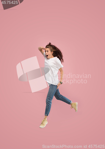 Image of Freedom in moving. Pretty young woman jumping against pink background