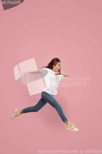 Image of Freedom in moving. Pretty young woman jumping against pink background