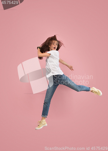 Image of Freedom in moving. Pretty young woman jumping against pink background