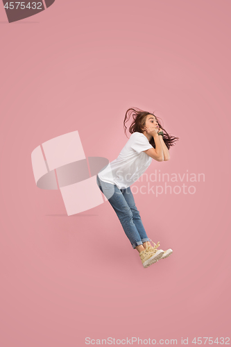 Image of Freedom in moving. Pretty young woman jumping against pink background