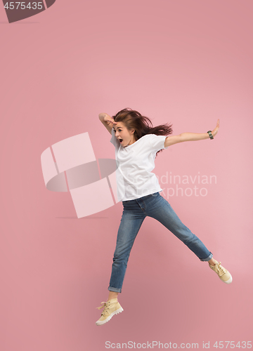 Image of Freedom in moving. Pretty young woman jumping against pink background