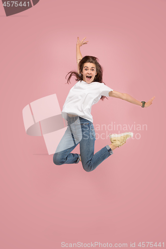 Image of Freedom in moving. Pretty young woman jumping against pink background