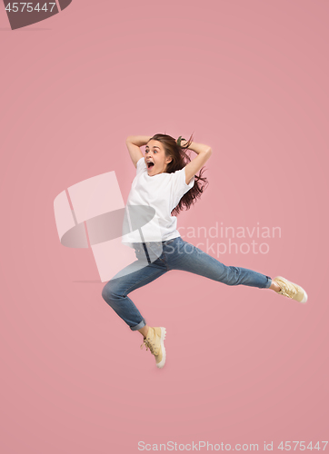 Image of Freedom in moving. Pretty young woman jumping against pink background